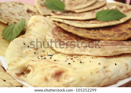 Selection of Indian breads, with naan in the foreground, and various stuffed parathas behind, garnished with mint leaves