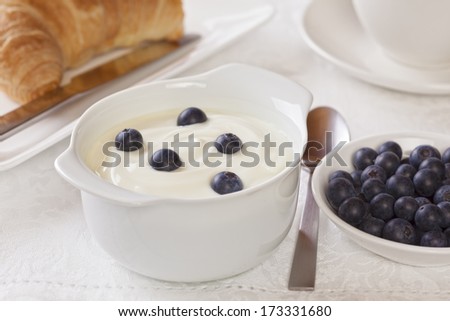 Yogurt and Blueberries Breakfast - Yoghurt with blueberries for breakfast with coffee and croissant.
