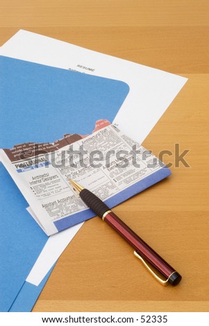 Blue folder with resume on desk, newspaper clipping and pen.