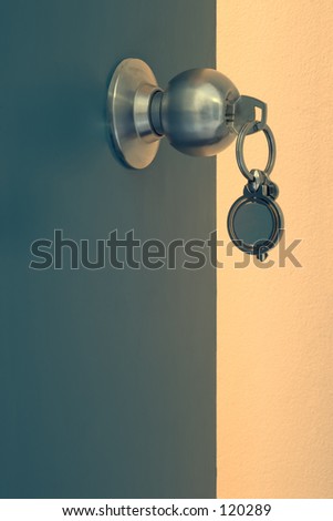 Close up of door with steel knob, key in lock, door standing open.