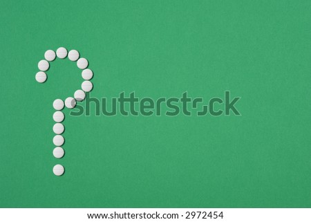 Aspirin tablets in shape of question mark, concepts of health, medical safety, green background to suggest alternative medicine or holistic therapy.