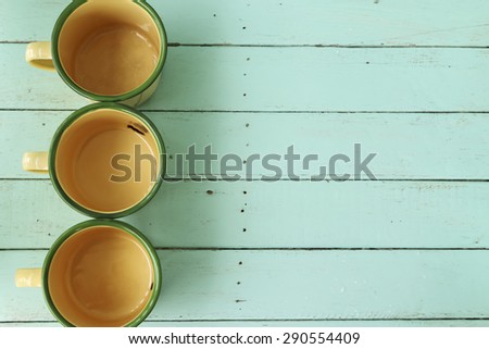 Three vintage cup decorated on green table for background.