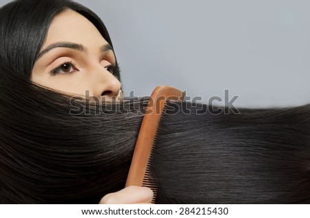 Close-up of woman combing her beautiful long hair over colored background