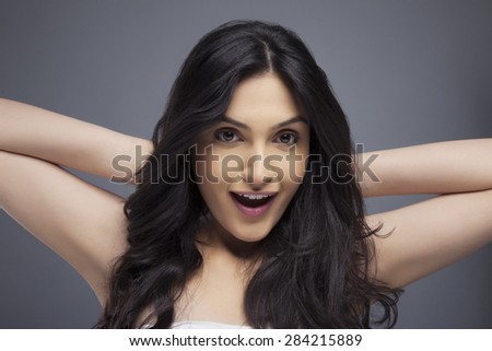 Portrait of an excited young female with long hair over colored background