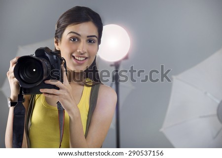 Portrait of young female photographer with digital camera in studio
