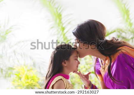 Woman kissing her daughters forehead