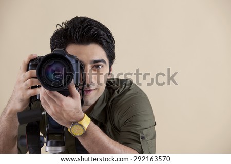 Close-up of young handsome photographer taking a photograph