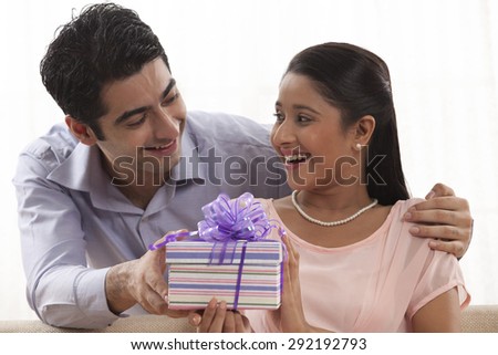 Handsome young man giving a gift to woman at home
