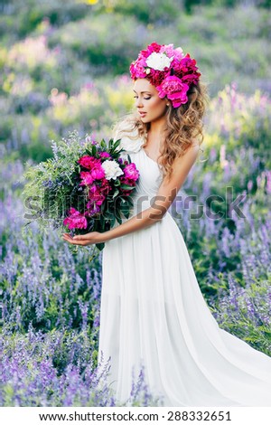 Fashion Beauty Model Girl with flowers in the hair in a wedding dress. Bouquet of peonies. Outdoor. soft focus