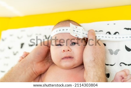 Shot of a pediatrician examining newborn baby. Doctor using measurement tape checking baby's head size. Closeup Stock fotó © 