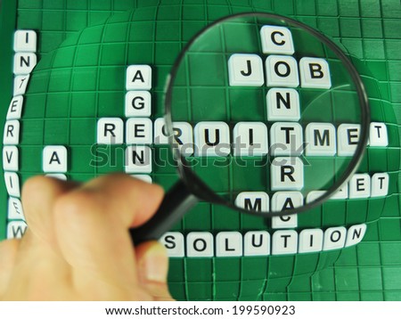 Hand and magnifying glass focused on job searching