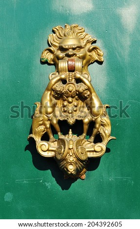 Detail of old door with vintage golden door knob against green grungy wood texture
