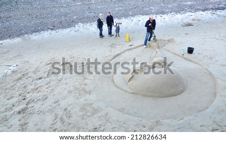 LONDON, UK - NOVEMBER 18, 2011: Tourists admiring sculptures in sand at outdoors art exhibition on Thames\' shore