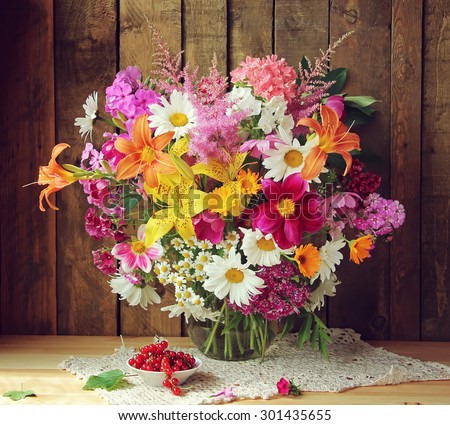 Still life with a summer bouquet of cultivated flowers and red currant