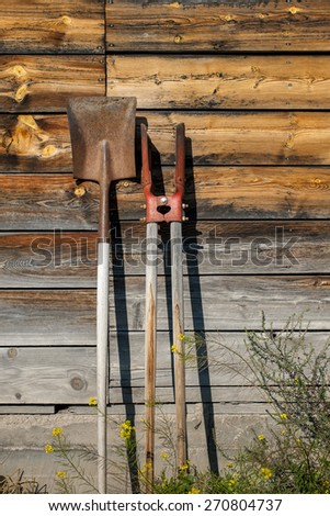 farm tools lean against a western barn wall