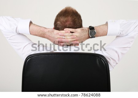 relaxation of the businessman in a black leather chef’s chair - back view