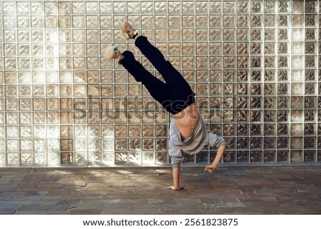 Similar – Image, Stock Photo Strong man performing handstand on sports ground