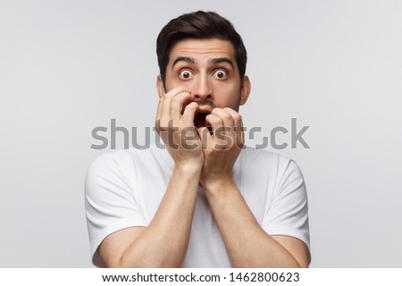 Young man covering mouth with hands and round eyes, wearing round eyeglasses, experiencing astonishment and fear, isolated on gray background Foto d'archivio © 