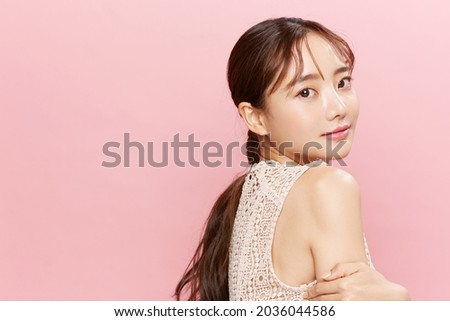 Beauty portrait of young Asian woman in dress on pink background.