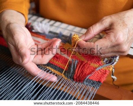 Master weaver is weaving the tapestry with diverse bright threads, close up. Artisanal at work 商業照片 © 