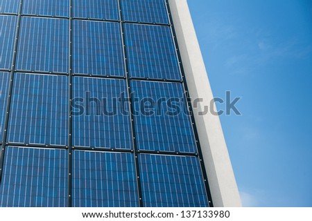 Blue solar cell panel on a wall reflecting the sun and the cloudless blue sky