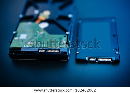 Hard disk next to ssd disk (solid state drive) blue technological background - tilt-shift lens used to accent the center of the hdd and to emphasize the attention their connections
