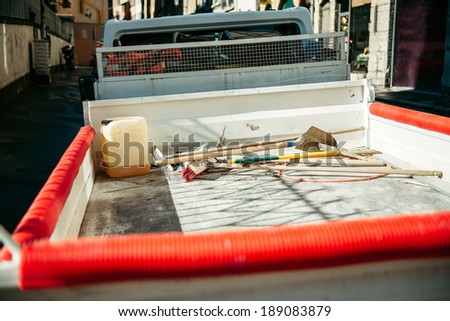 Utility service van vehicle in town - rear trunk view with diverse tools inside - shovels, rakes and broom