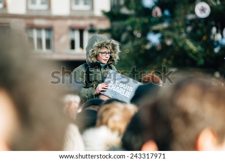 STRASBOURG, FRANCE - 11 JAN, 2015:  Kid holding placard reading \'Je suis Charlie\' during a unity rally (Marche Republicaine) where some 50000 took part in tribute three-day killing spree in Paris