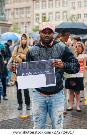 STRASBOURG, FRANCE - APR 26 2015: I am a migrant poster holed by a man at protest against immigration policy and border management which asks for commitment in the wake of migrants boat disasters