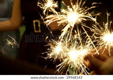 People holding beautiful sparklers (fire crackers) in hands on a birthday, Christmas or New Year party. Useful file for the upcoming holidays and parties.