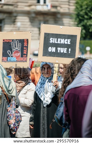 STRASBOURG, FRANCE - JULY 11, 2015: Silent killing placard - Uyghur human rights activists participate in a demonstration to protest against Chinese government\'s policy in Uyghur