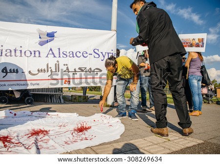 STRASBOURG, FRANCE - AUG 20, 2015: People protesting in front of European Parliament denouncing the Syrian airstrikes on Douma wheremore 80 were killed - blood immitation on white scarf