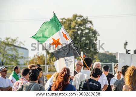 STRASBOURG, FRANCE - AUG 20, 2015 People protesting in front of European Parliament denouncing the Syrian airstrikes on a Damascus suburb of Douma which killed more than 80 people - waving syrian flag