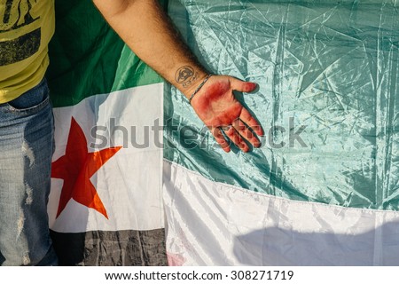 STRASBOURG, FRANCE - AUG 20, 2015: People protesting in front of European Parliament denouncing the Syrian airstrikes on Douma wheremore 80 were kille - syrian war Tattoo on hand and Syrian flag