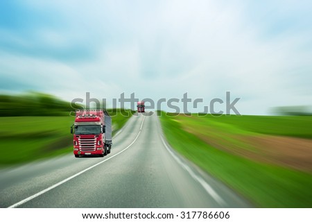 Red trucks on blurry highway and green field driving for fast delivery of goods, parcels and industries