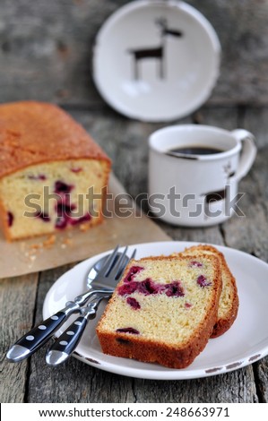 Cup of coffee or tea with a cherry cake on a wooden dinner-table