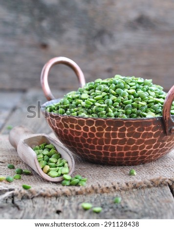 Dried green split peas in a copper plate on a wooden table