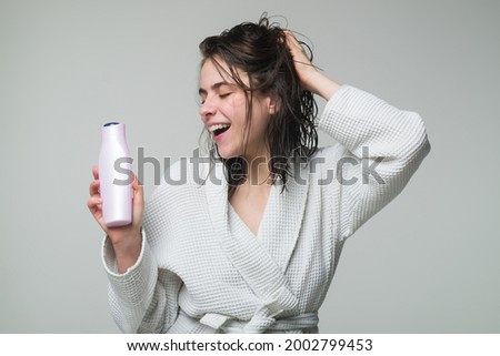 Woman touching her hair. Woman hold bottle shampoo and conditioner. Happy young woman with balm bottle applying hair mask. Beauty product.