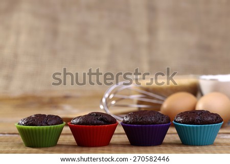 Chocolate cupcakes in a row in colored silicone bakewares blue green red and violet colors copyspace, horizontal photo
