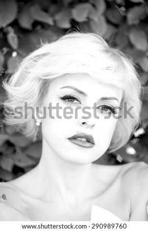 Portrait of alluring passionate woman with short hair looking forward on natural background black and white, vertical picture