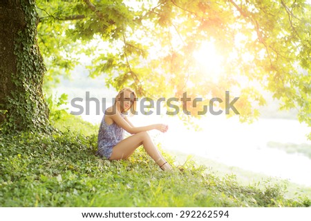 Sweet pensive slender girl outdoor in summer clothes near water on green natural background copyspace, horizontal picture