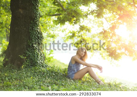 Sweet thoughtful slender woman outdoor in summer clothes in park on green natural background, horizontal picture