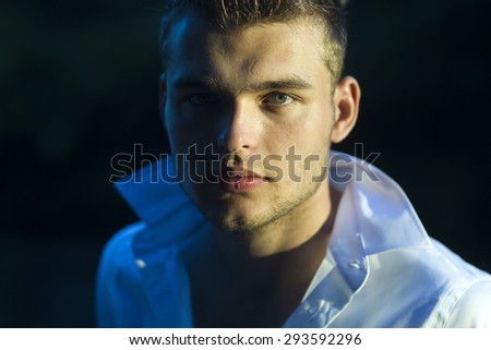 Portrait of young sexual handsome macho man model with beautiful face with dimple in white shirt in sunset on outdoor background, horizontal picture
