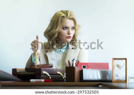Beautiful serious sexy business woman sitting at table with many office appliances holding knife for cutting paper looking away on white background, horizontal picture