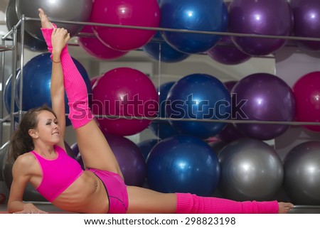 Sexual pretty smiling sporty fitness girl in pink with flexible body stretching lying on floor in training hall on sport balls background copyspace, horizontal picture