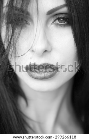 Portrait of beautiful sexual young lady with hard look bright makeup plump ripe lips long neck and beauty spot looking forward closeup black and white, vertical picture
