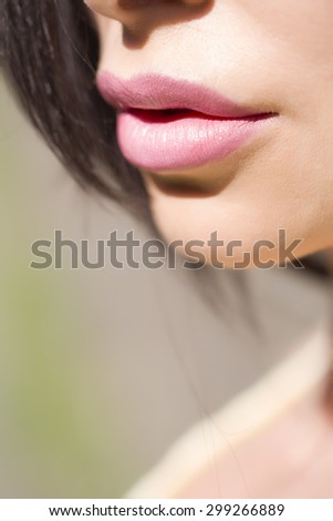 Closeup of soft beautiful female face with pink juicy lips tender chin and fine skin of young brunette girl sunny day outdoor, vertical picture