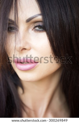 Portrait of pretty sexy young woman with hard look bright makeup plump ripe lips long neck and black hair looking away closeuo, vertical picture