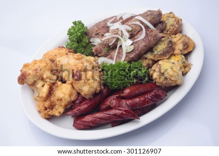 Snack plate of delicious grilled browned sausages with shish kebabs decorated roasted mushrooms stuffed with cheese fried cauliflower and parsley isolated on white, horizontal picture