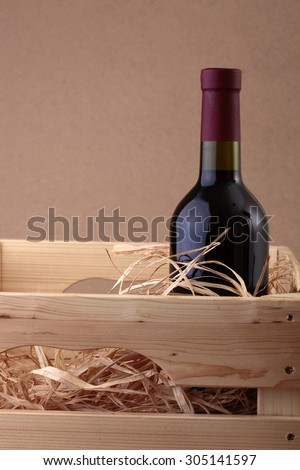 One glass wine corked new bottle full of alcohol red beverage wrapped in straw standing in wooden box on paper background copyspace, vertical picture